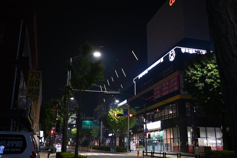 어두운 밤거리에 켜진 가로등과 건물 조명이 대비를 이루며 도시의 밤 풍경을 보여주는 사진입니다.