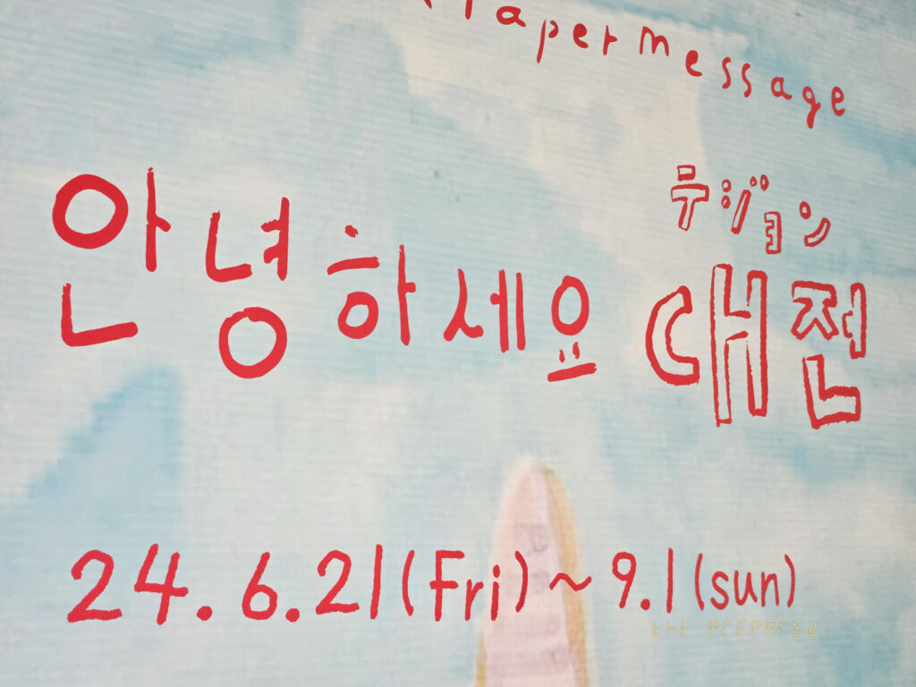 흐릿한 배경의 밝은색 표지판. 맨 위에는 "a paper message"라는 문구가 흐릿하게 적혀 있습니다. 오른쪽에 "대전"이라는 단어가 쓰여 있고, 그 아래에 붉은색 글씨로 "안녕하세요 대전"이라고 적혀 있습니다. 맨 아래에는 "24.6.21(금) ~ 9.1(일)"이라는 문구가 있습니다.