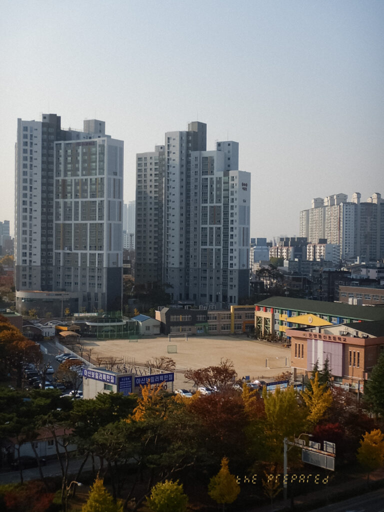 고층 아파트 단지와 학교 운동장이 보이는 탁 트인 도시 풍경 사진입니다.