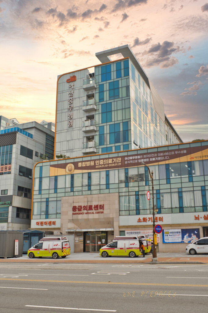 병원은 응급 의료 센터, 어린이 센터, 소화기 센터, 뇌·혈관 센터 등 다양한 진료과가 있는 종합병원이며, 구급차 두 대가 응급 의료 센터 앞에 정차하고 있습니다.