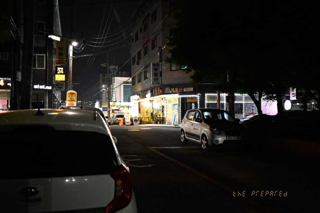 어두운 밤, 자동차와 건물, 가로등 불빛이 어우러진 아산의 한적한 골목길 풍경 사진입니다.