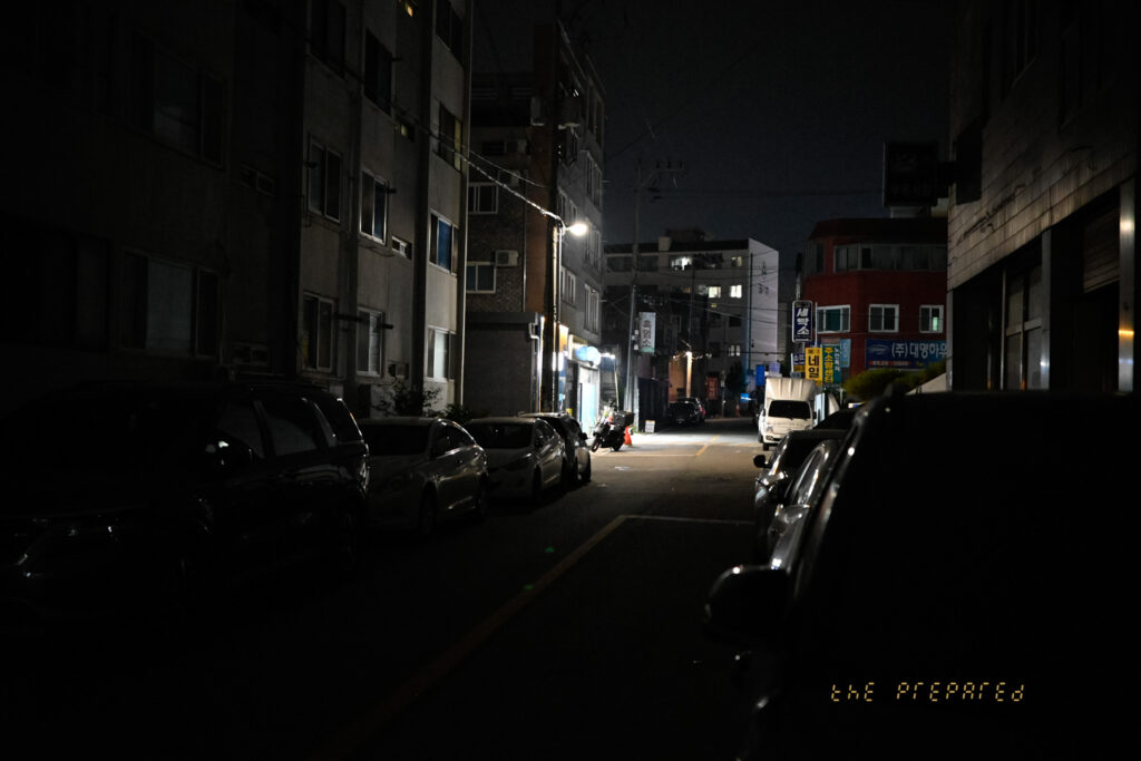 어두운 밤, 자동차와 건물, 가로등 불빛이 어우러진 아산의 한적한 골목길 풍경 사진입니다.