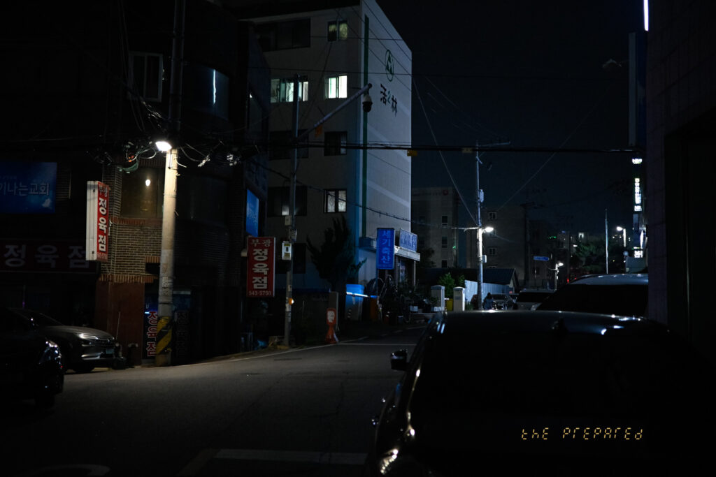 어두운 밤, 자동차와 건물, 가로등 불빛이 어우러진 아산의 한적한 골목길 풍경 사진입니다.