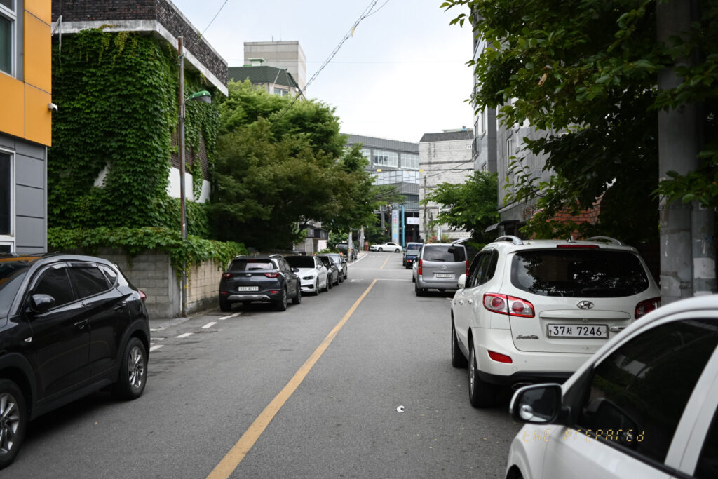 이 사진은 아산시 충청남도 한적한 거리를 담고 있습니다. 2010년 현대 싼타페 흰색 차량이 도로 옆에 주차되어 있는 모습이 중앙에 보입니다.