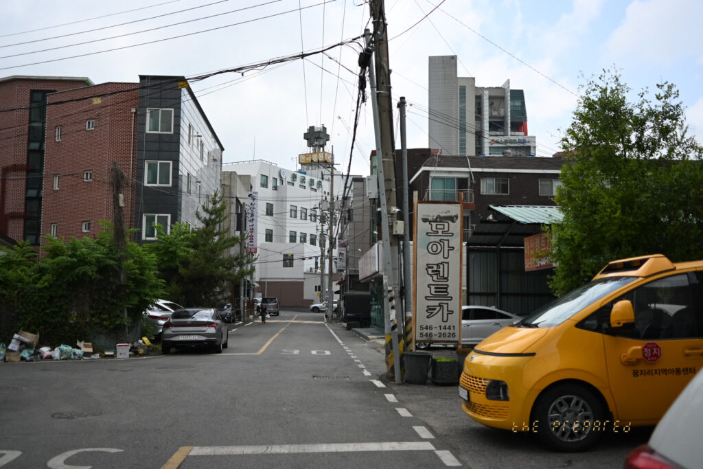 골목길 사진에 전봇대, 렌터카 간판, 지역아동센터 표지판 등이 추가됨.